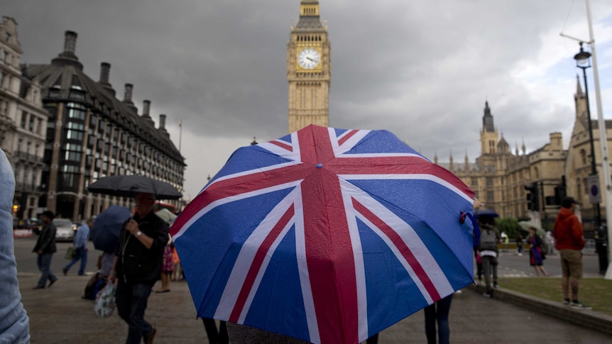 A person near Big Ben uses a large Union Jack umbrella.