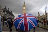 A person near Big Ben uses a large Union Jack umbrella.