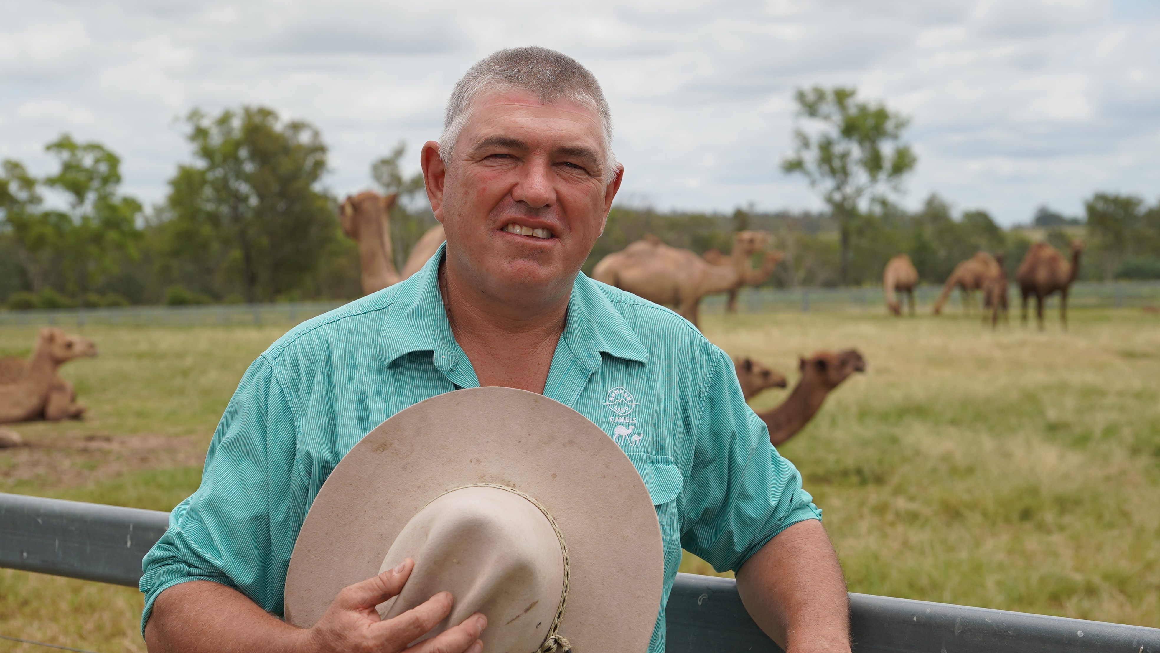 Un granjero con camellos al fondo.