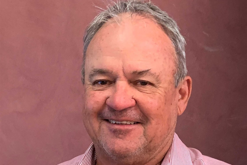 An older man with thinning grey hair, smiling for a portrait shot.