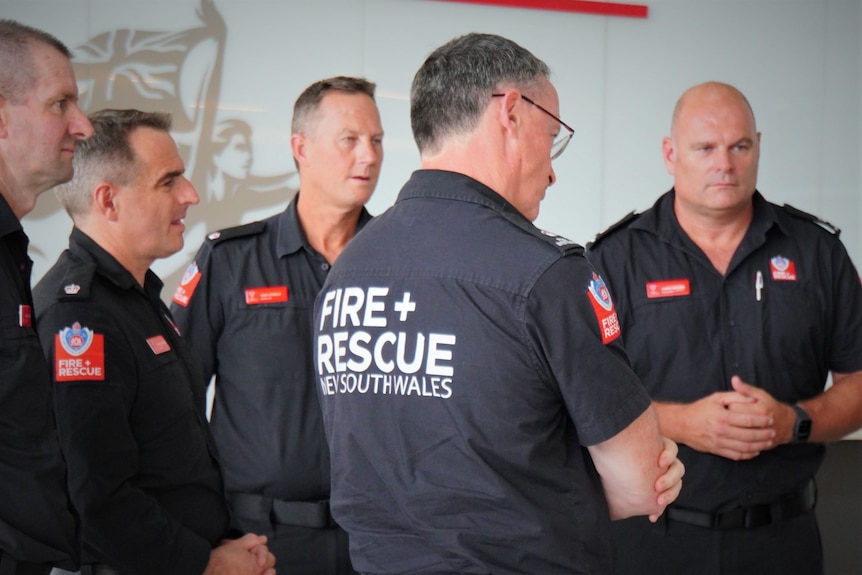 Five men in navy blue uniforms stand in a group.