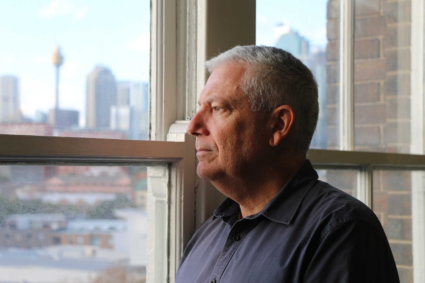 David Westgate looks out a window at the Sydney city skyline.