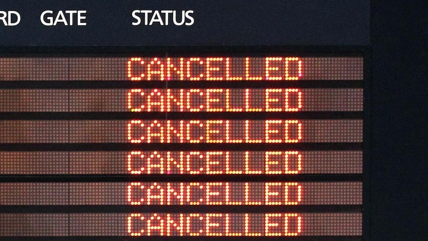 An airport departure board shows cancelled flights