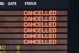 An airport departure board shows cancelled flights