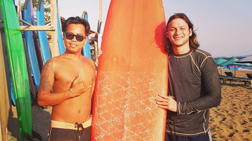 Two men pose with surfboards