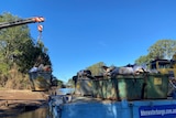 crane lifts skip bin full of rubbish off a barge and onto land