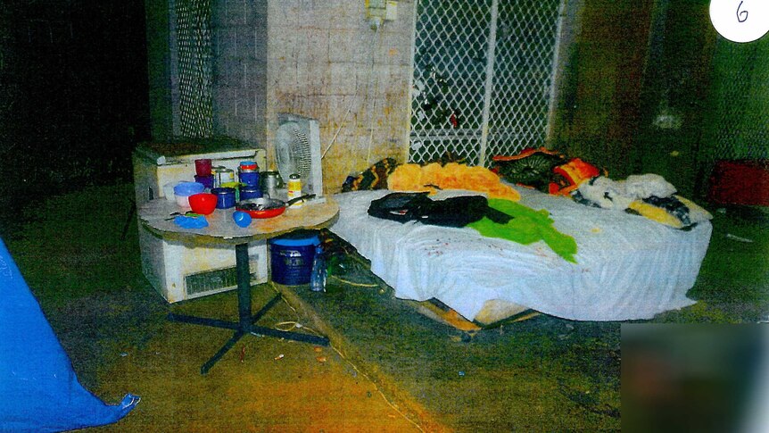 A squalid looking area with a mattress  and kitchen items.