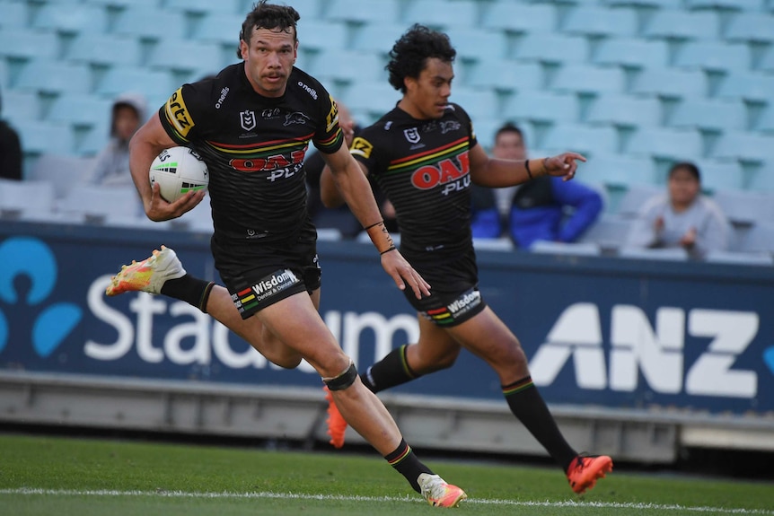 A rugby league player runs with the ball under his arm.