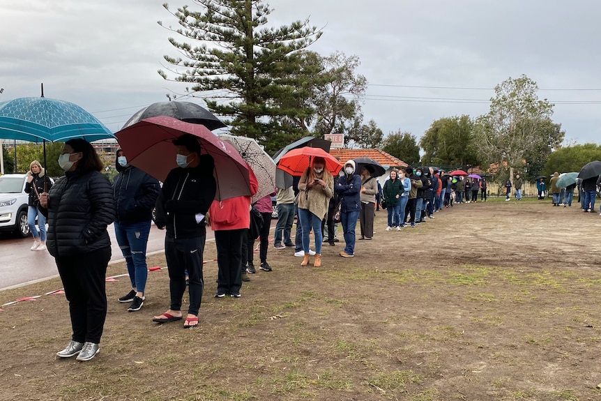 A queue of people holding umbrellas.