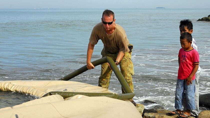 Sapper Jonathon Tidboald places a water pipe into a staging tank