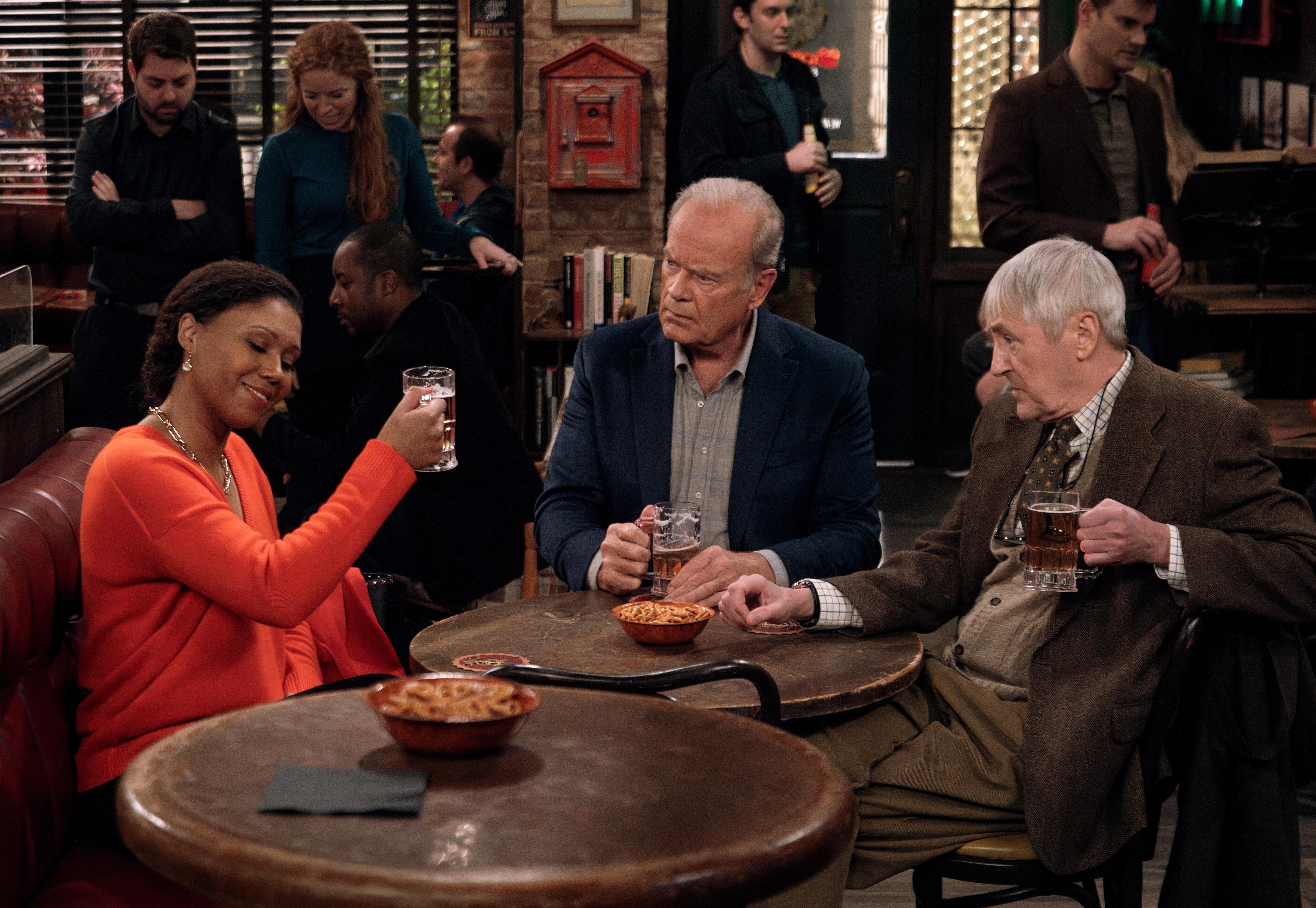 A woman and two men sit at a table in a bar.