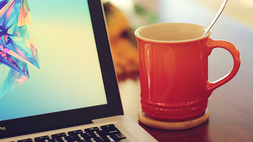 A laptop and soup in a mug.