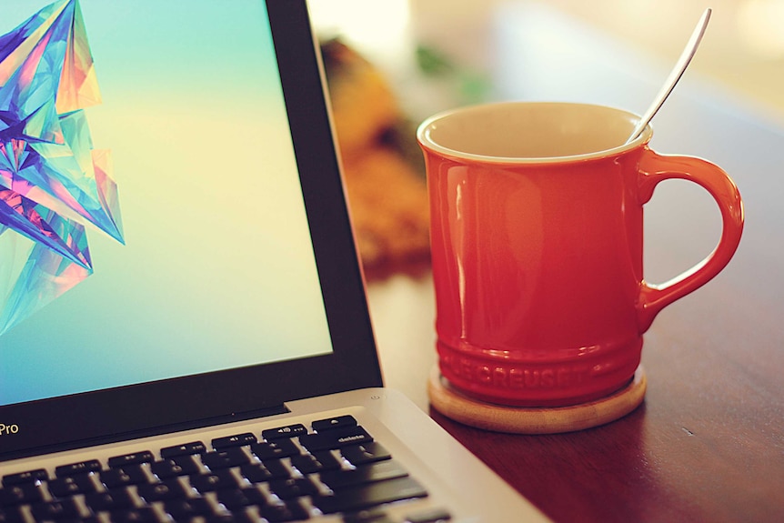 A laptop and soup in a mug.