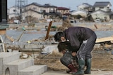 A woman cries in front of her damaged home in the town of Watari