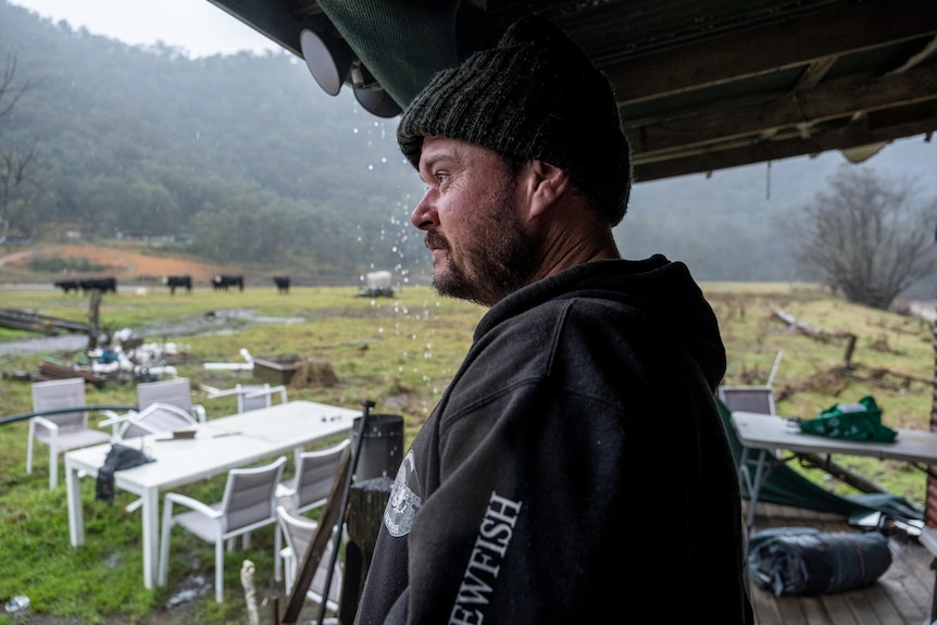 a man wearing a beanie looking as rain falls