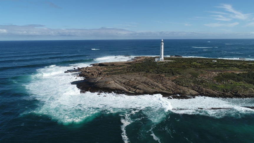 A lighthouse standing on a rocky outcrop, surrounded by ocean.