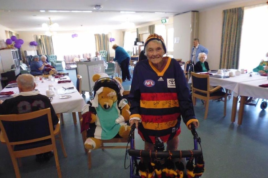 An elderly woman wearing an AFL guernsey as a supporter
