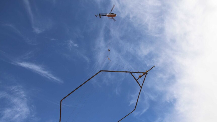 A helicopter lifts a giant electro-magnet