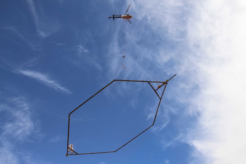A helicopter lifts a giant electro-magnet in the Murchison