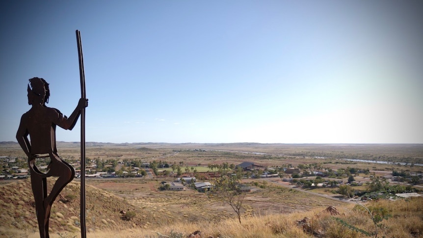 Image of a statue of a man holding a spear overlooking the community of Roebourne.