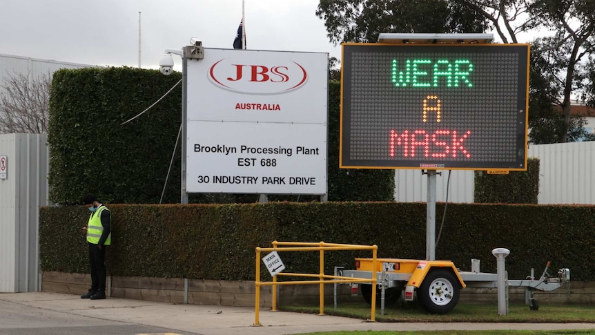 An electric sign saying 'wear a mask' outside a JBS abattoir.