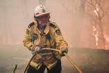 A firefighter pulls a hose in a blaze