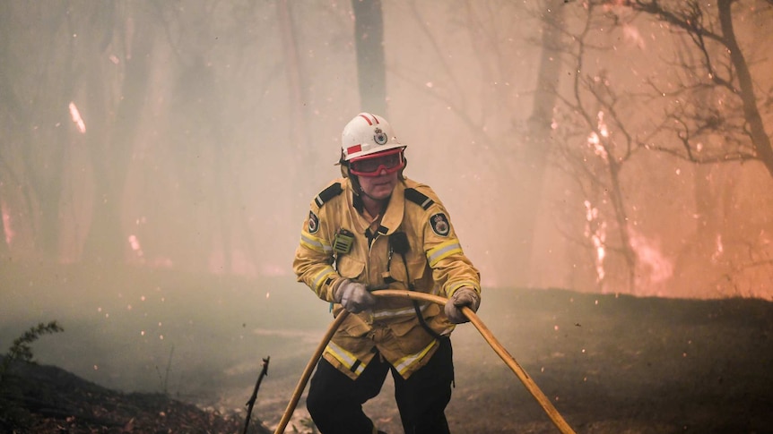 A firefighter pulls a hose in a blaze