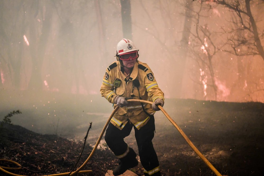 A firefighter pulls a hose in a blaze