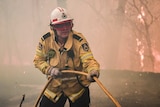 A firefighter pulls a hose in a blaze