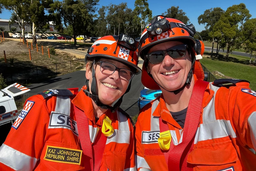 Two SES volunteers in orange uniforms smiling at the camera.