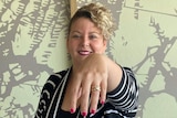Smiling woman holding out hand with gold ring on finger