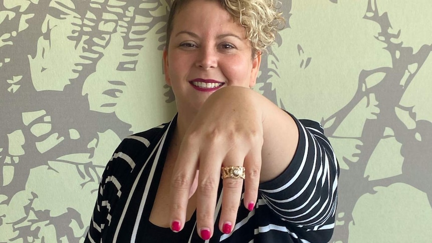 Smiling woman holding out hand with gold ring on finger