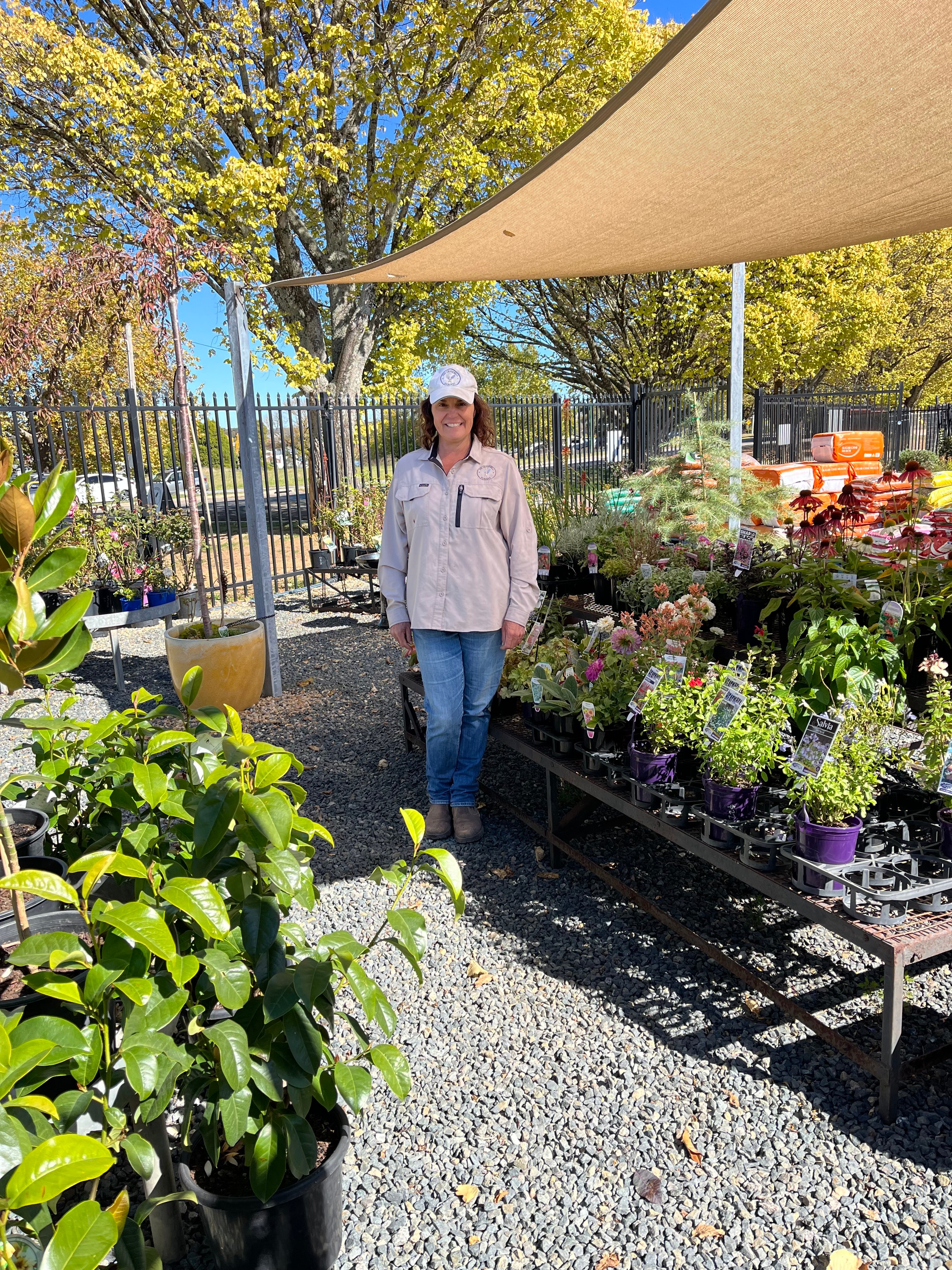 La mujer se encuentra entre los árboles jóvenes sonriendo.