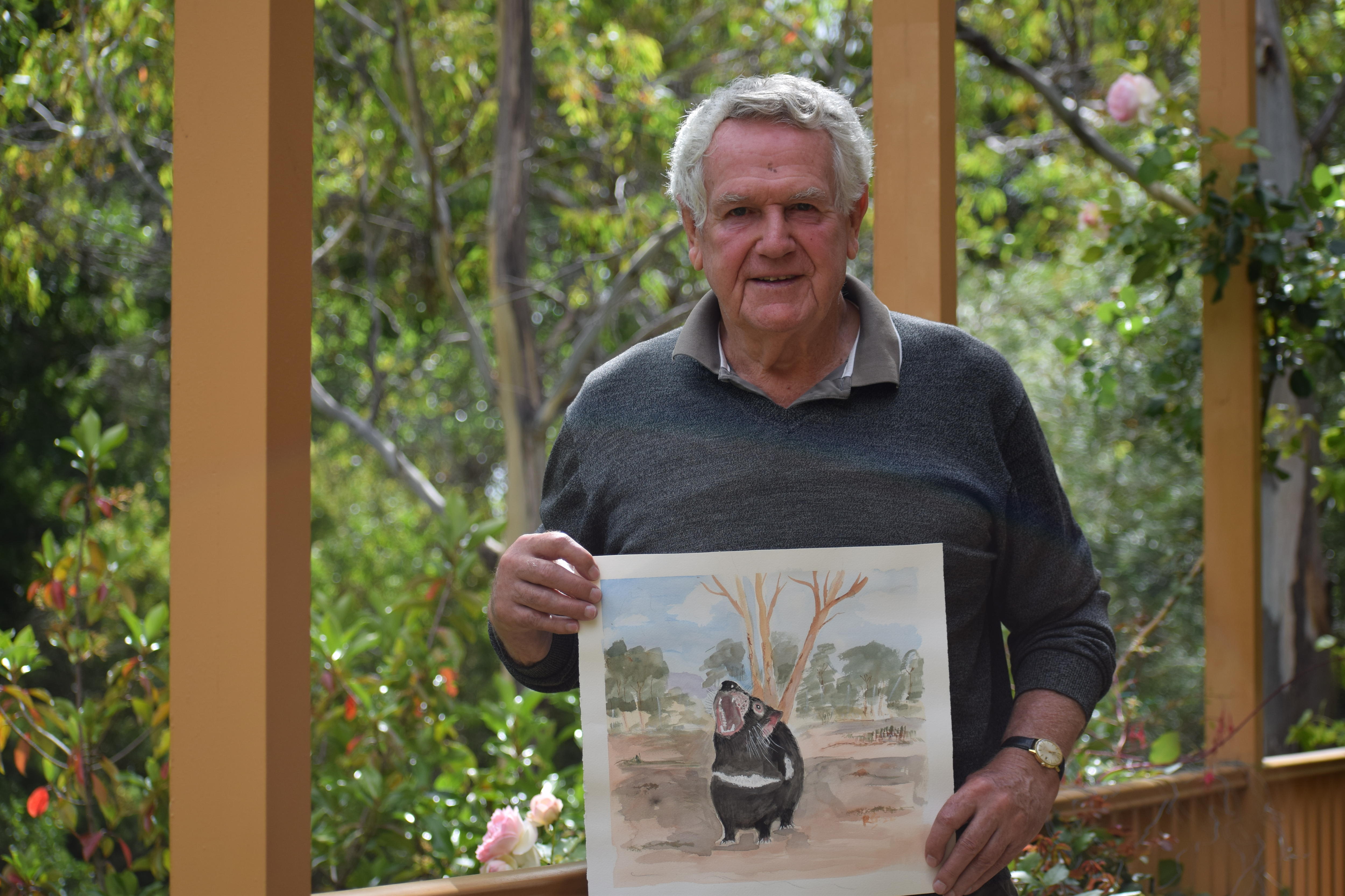 Man holding watercolour painting of a growling devil