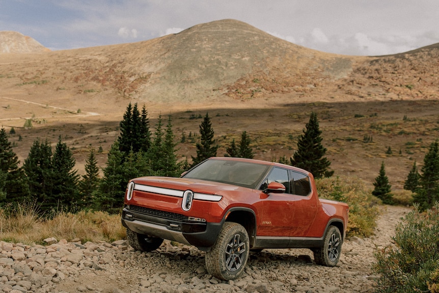 A red electric pick-up truck parked in the desert.