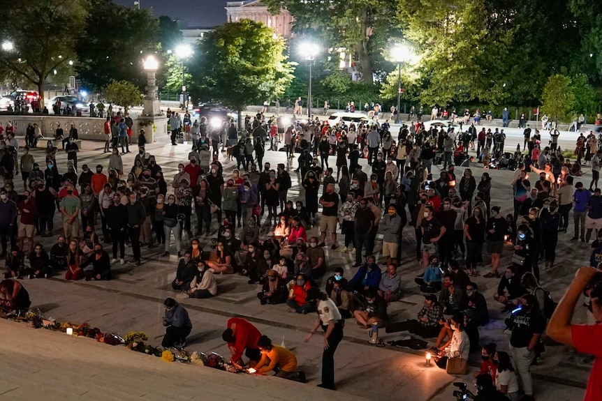 Crowds of people gather at night at the Supreme Court in Washington