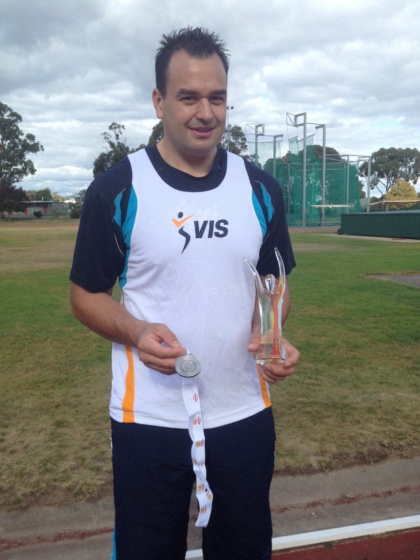 Paralympian Todd Hodgetts holding medal and trophy.