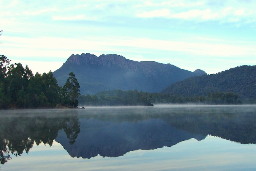 A mountain and trees are reflected in a lake.