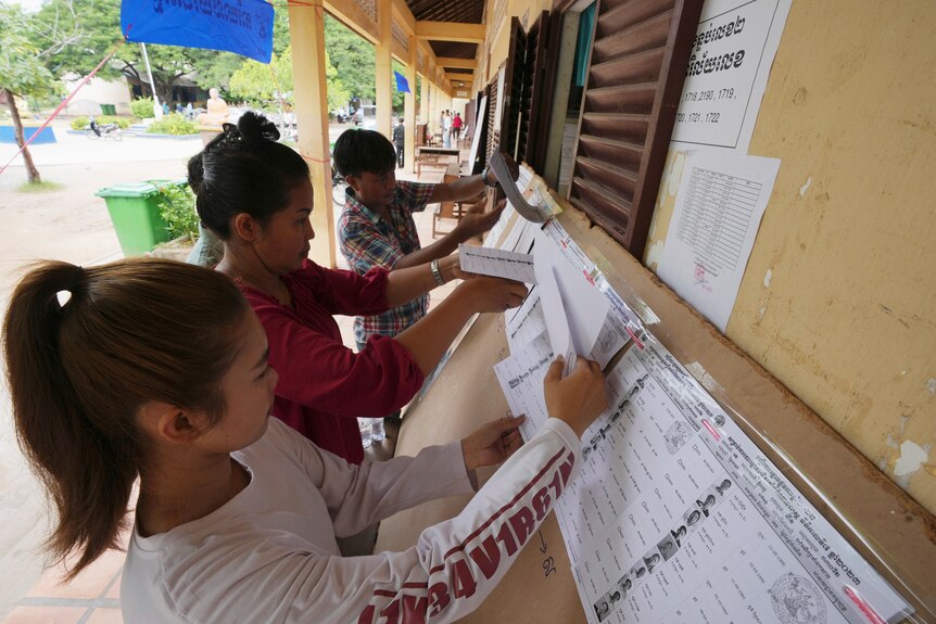 Locals look at a registration list before voting at a polling station on the outskirts of Phnom Penh.