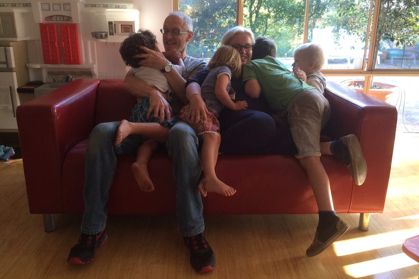 Sharon (right) and Kim Greenock sit on the couch with their four foster children.