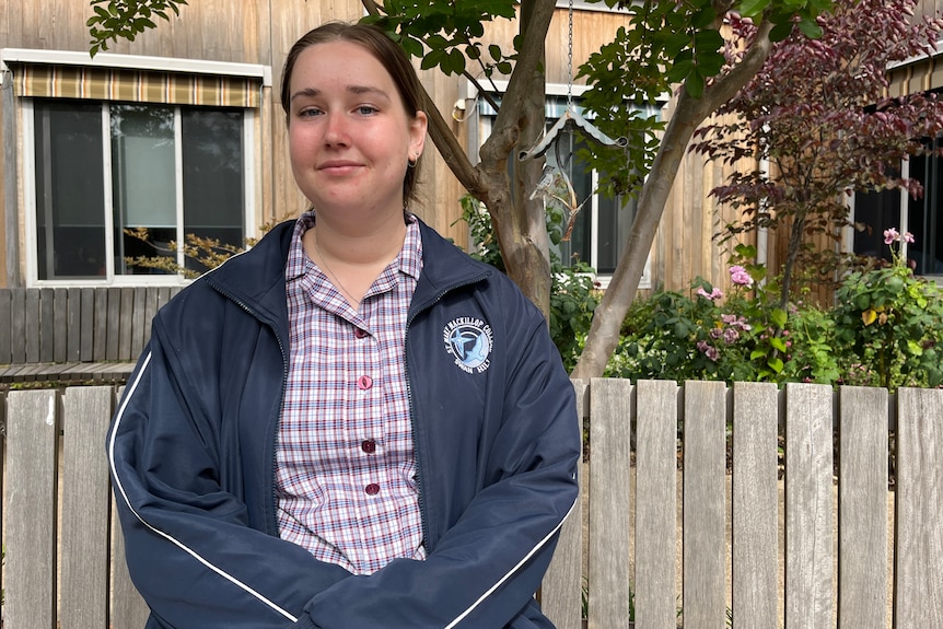 A female sitting on a park bench in a garden.