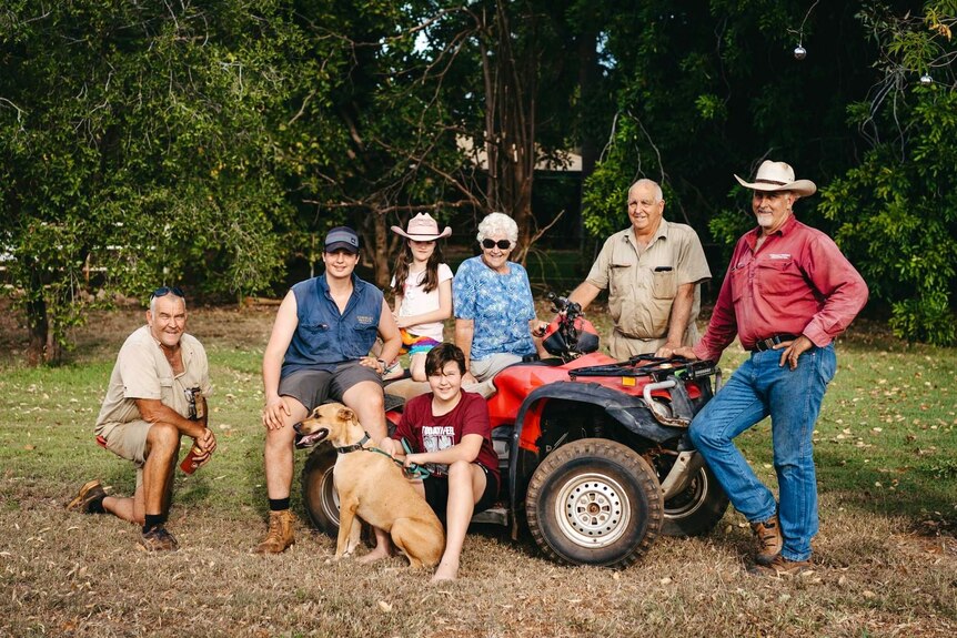 Seven family members posing around a quad bike with a dog