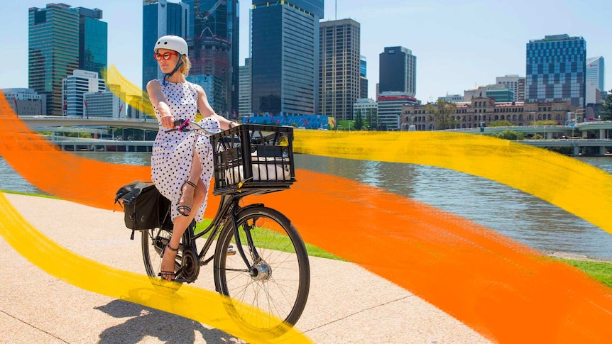 ABC radio presenter Katherine Feeney riding her bike along the Brisbane River in a dress and heels