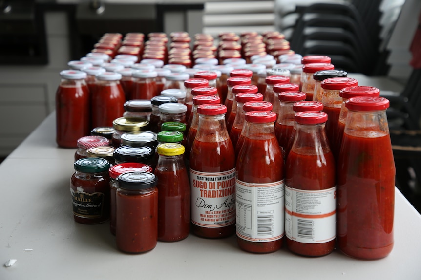 a table covered with full jars and bottles of passata