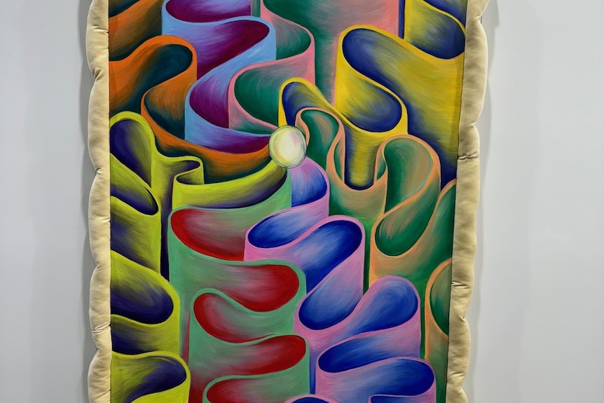 Una obra de arte multicolor de un orbe blanco en el centro, con ondas coloridas en forma de cintas que fluyen hasta el borde de la pintura.