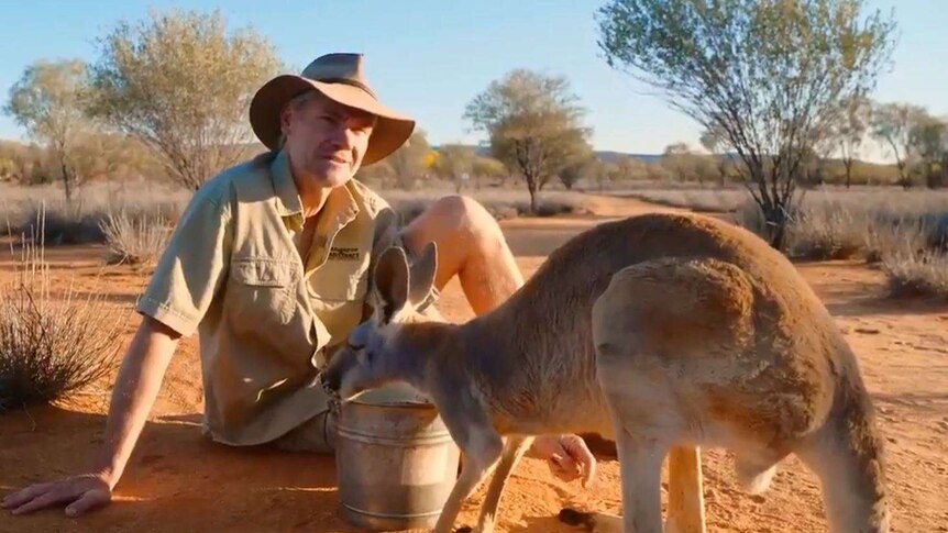 Chris Barns and a kangaroo sit in the outback in the new Tourism Australia campaign, 'Philausophy'