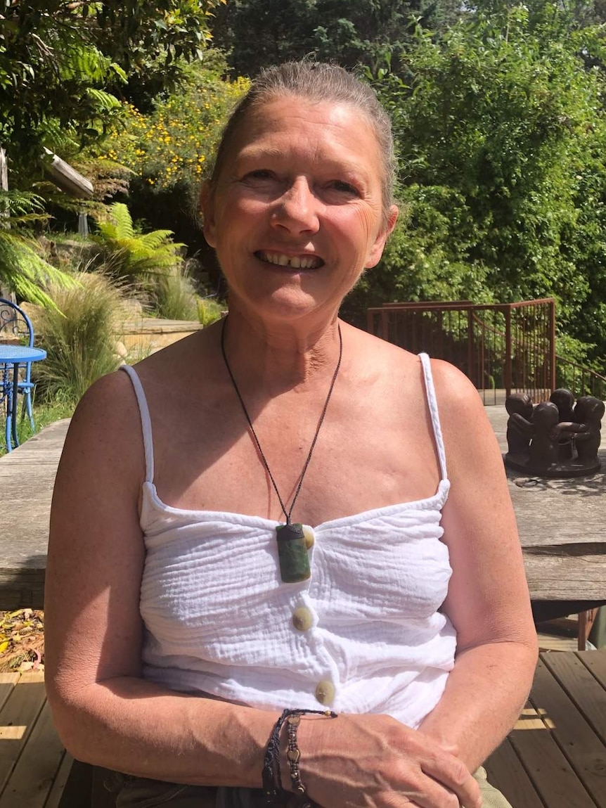 A woman wearing a summer singlet sits in the sun.