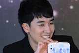 A picture of Big Bang singer Seungrri holding a phone with a cover of his band.