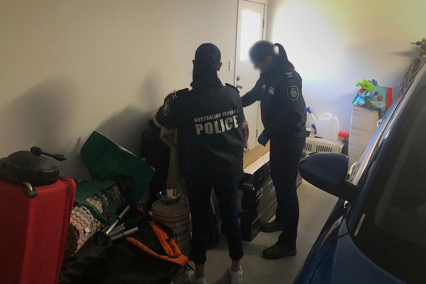 Two police officers search through the contents of a home