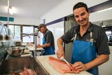 two men prepare fresh fish in their shop